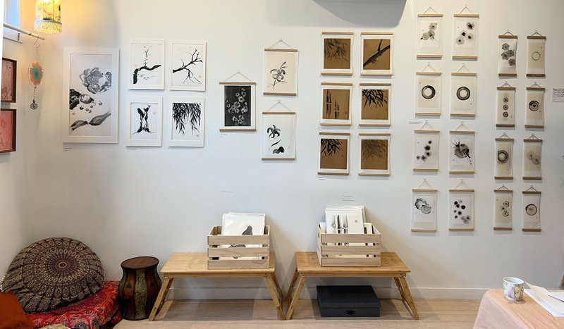 a gallery view of many sumi-e (ink brush) paintings on a white wall.
